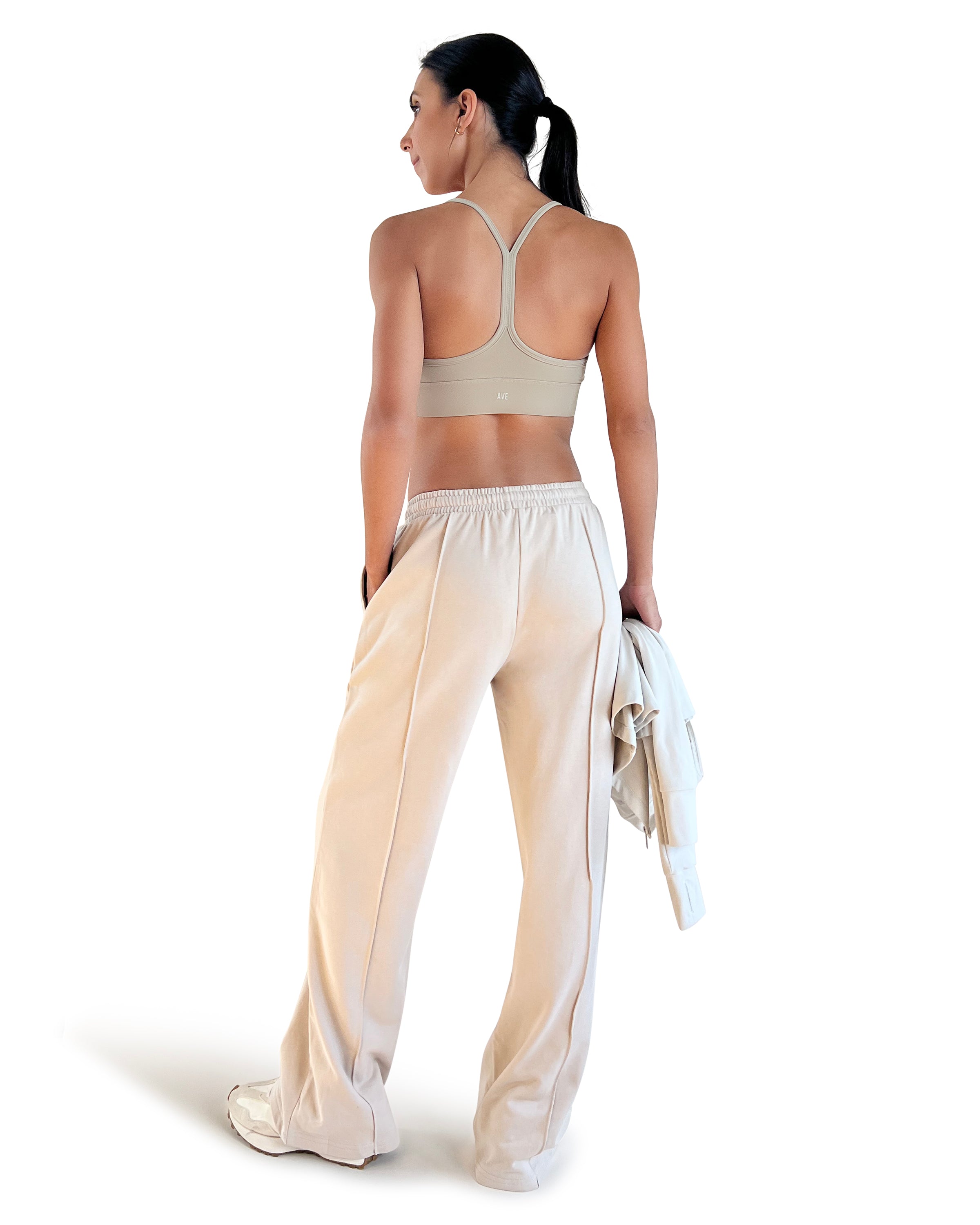 Beige cotton wide leg lounge pants with elastic waistband, side pockets and relaxed full-length fit, styled with a racerback sports bra for effortless athleisure wear.