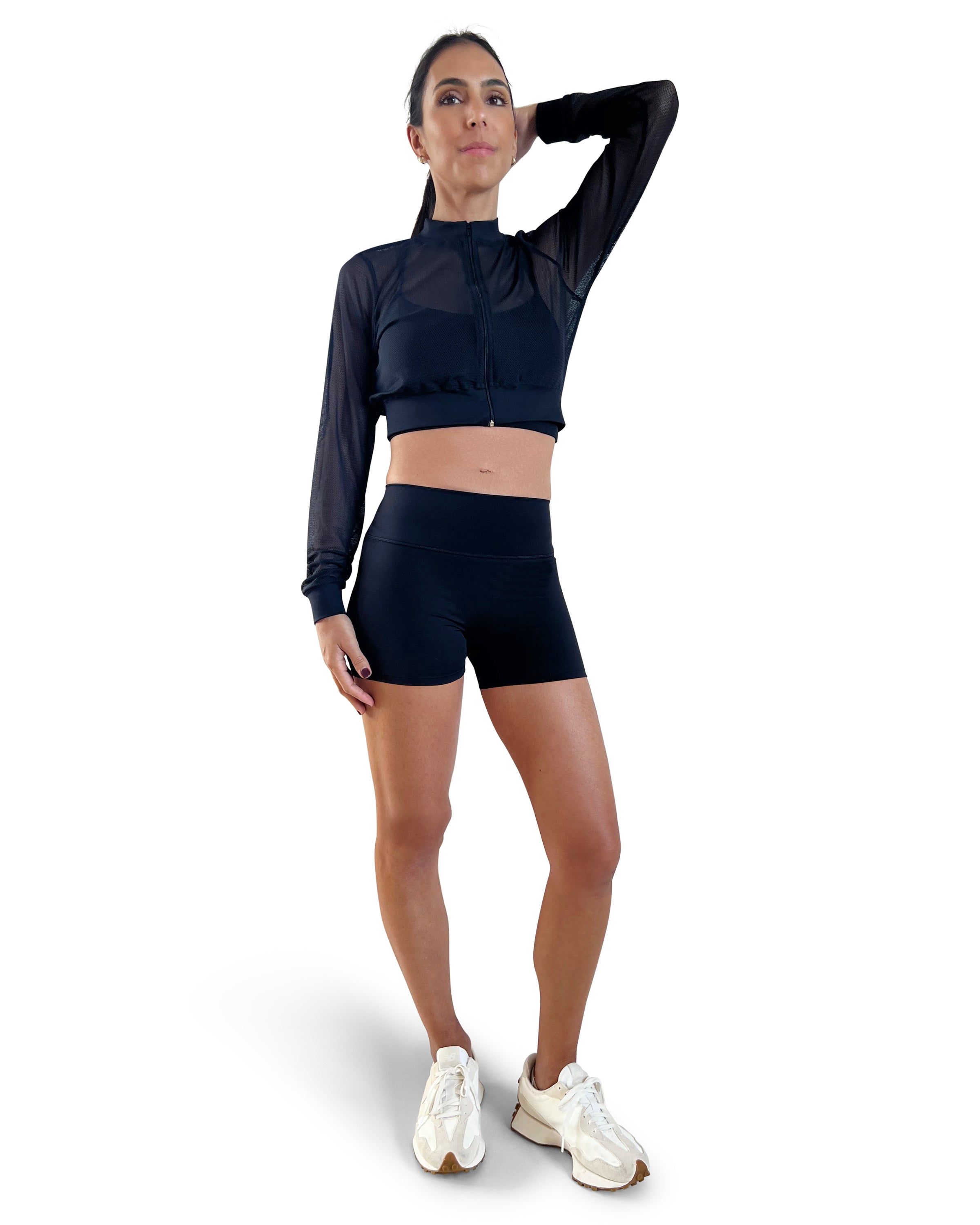 Woman in a black athletic outfit with mesh sleeves on a white background.