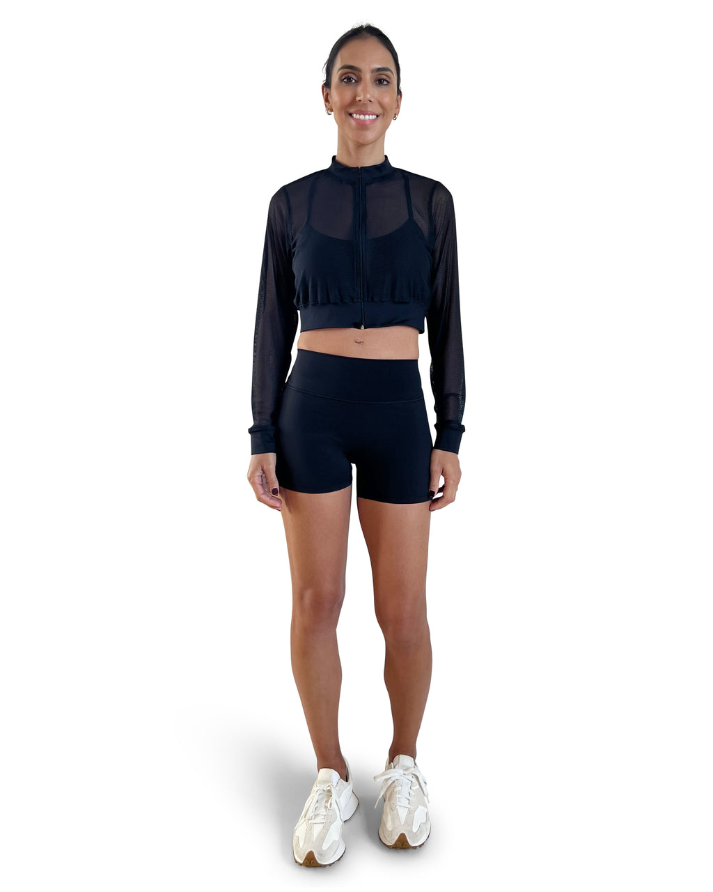 Woman in a black athletic outfit with mesh sleeves on a white background.