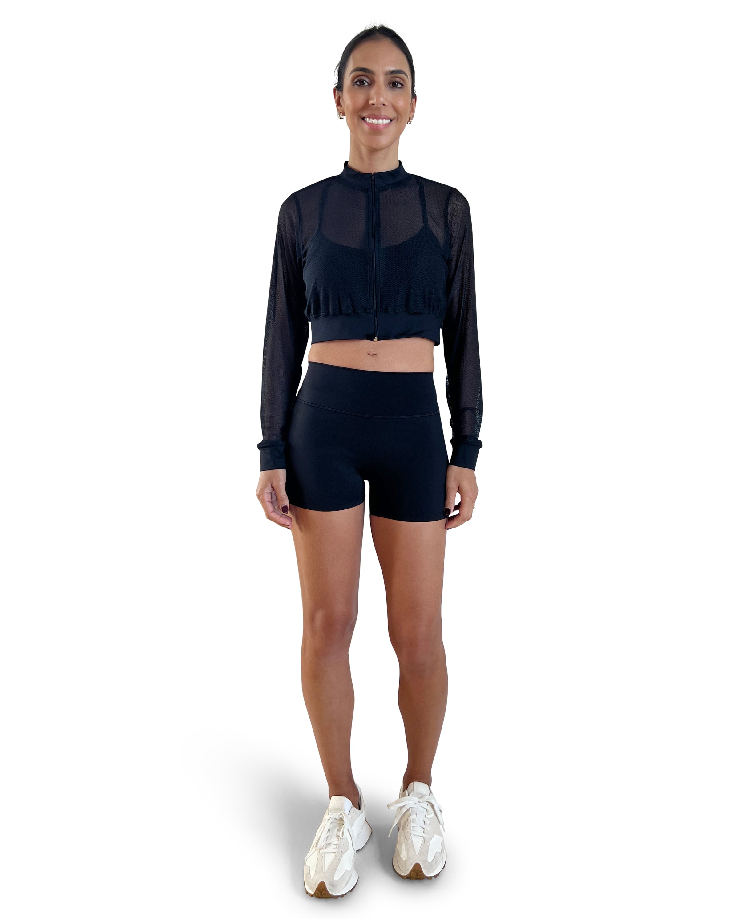 Woman in a black athletic outfit with mesh sleeves on a white background.