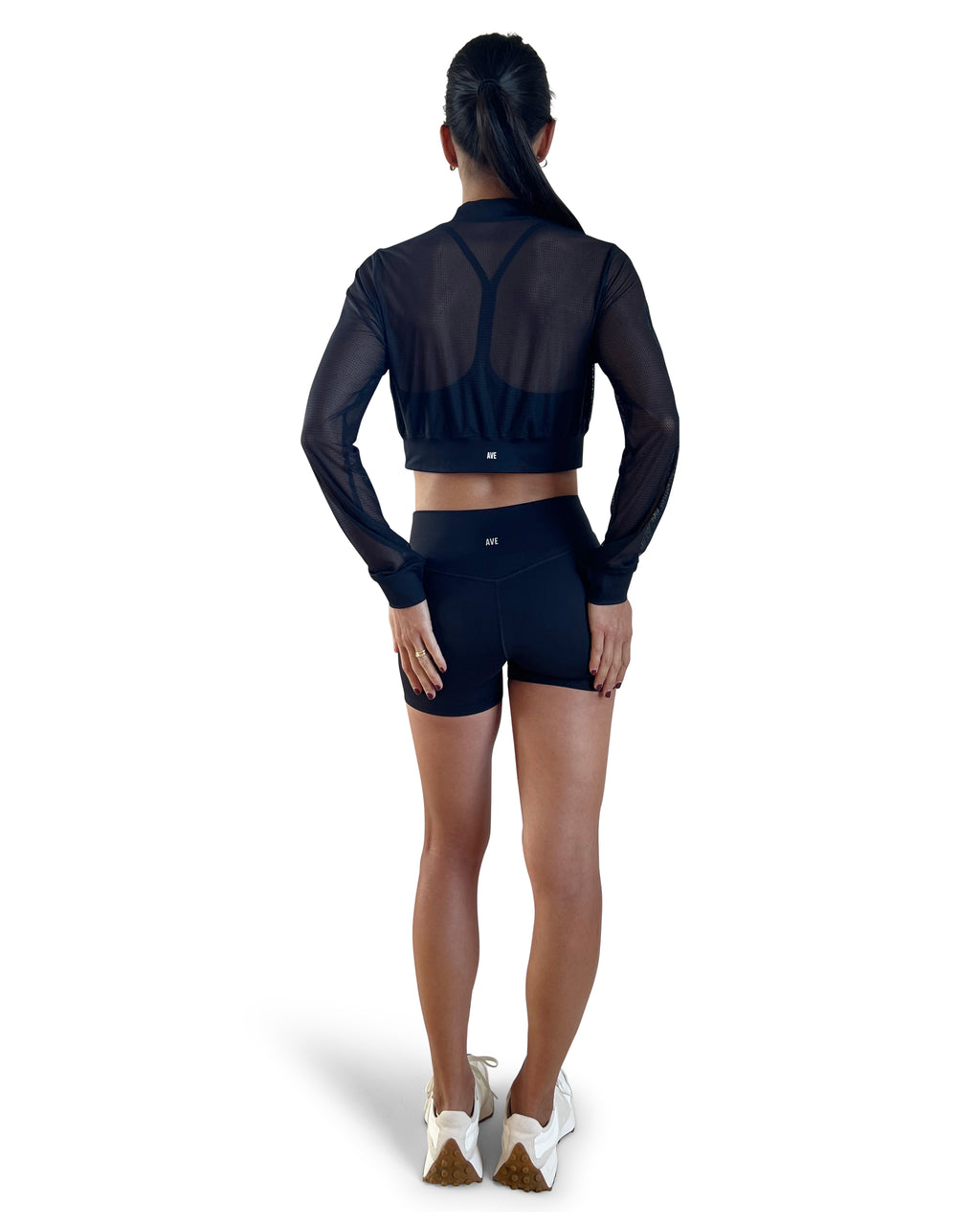 Woman in a black athletic outfit with mesh sleeves on a white background.