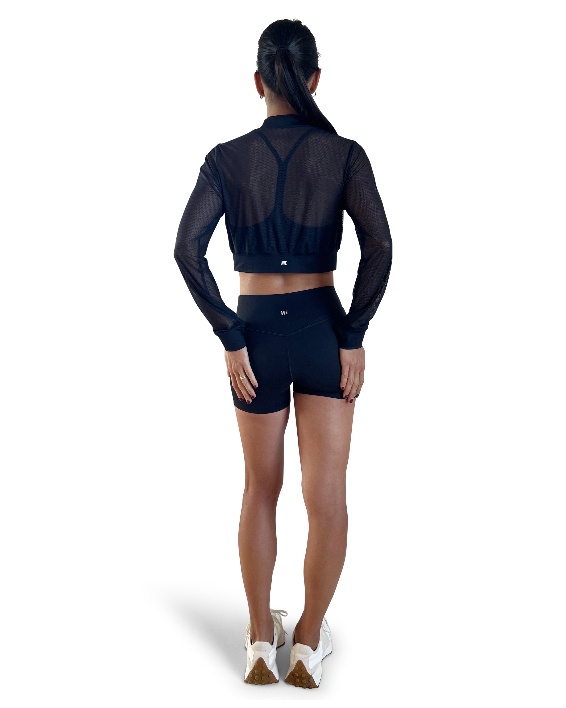 Woman in a black athletic outfit with mesh sleeves on a white background.