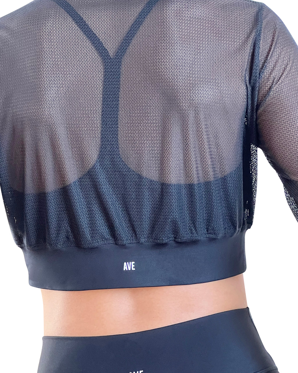 Woman in a black athletic outfit with mesh sleeves on a white background.