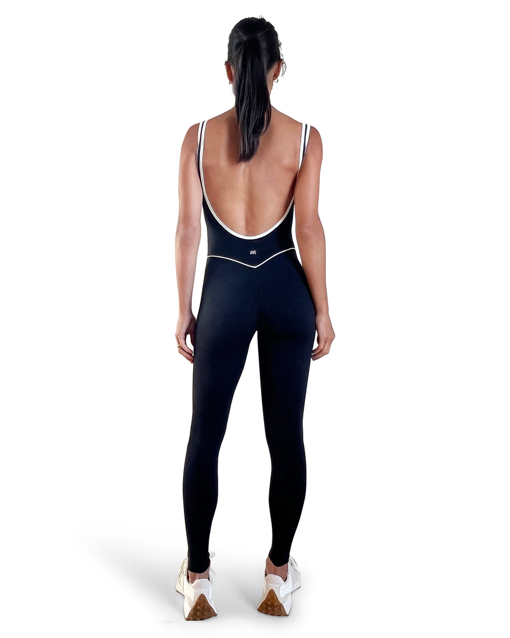 Women's black full-length yoga jumpsuit with white contrast trim, scoop neckline, and open-back design, featuring a sculpting fit for yoga, Pilates, and activewear.